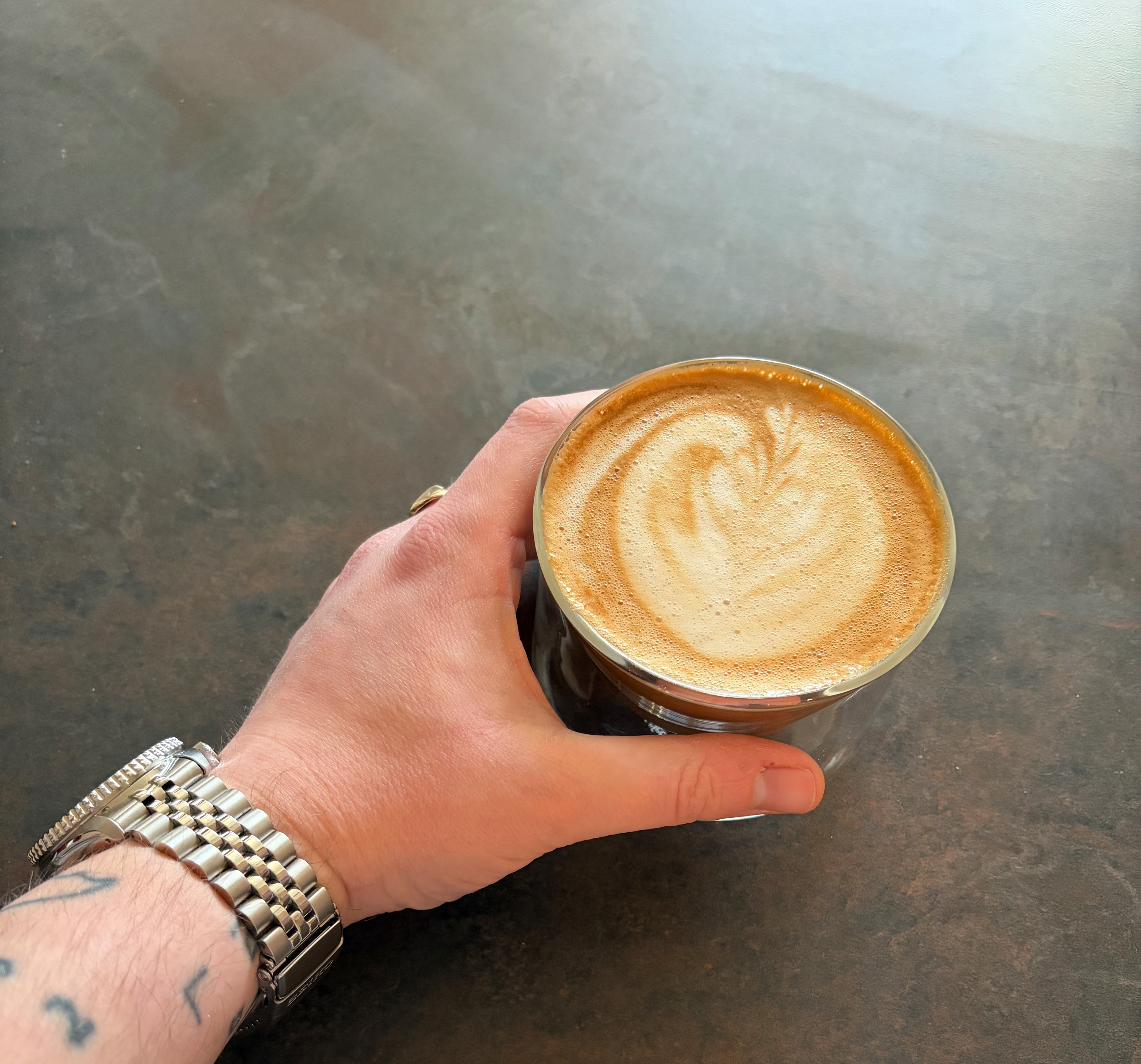 Hand holding a coffee cup with coffee on a countertop